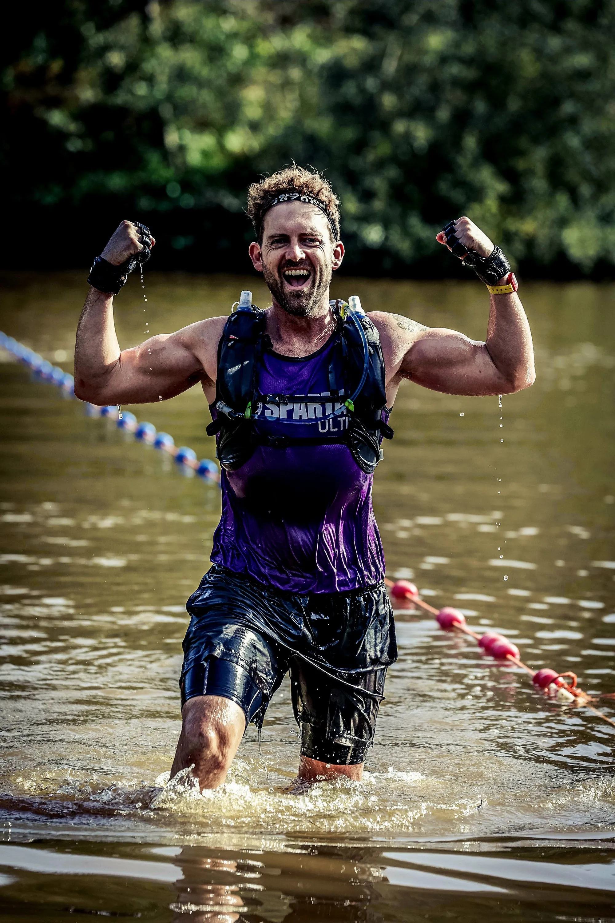 Coach Dave punching the air as he comes out of the water during a Spartan Ultra